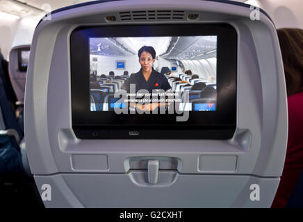 Airplane safety video on chairback screen of Delta Airlines Boeing 737, warning to keep seat belt fastened. Stock Photo
