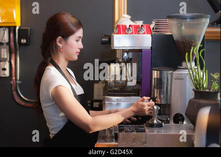 Female bartender makes coffee using coffee machine. Stock Photo