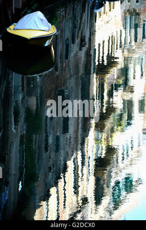 Yellow Boat on Canal With Buildings Reflected in Water, Venice, Italy Stock Photo