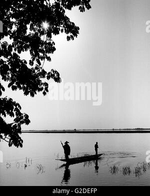 Silhouette of Two Men in Canoe Fishing on River Stock Photo