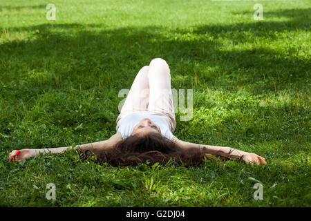 Young woman Caucasian-Asian sleeping laying on the grass in the park Stock Photo