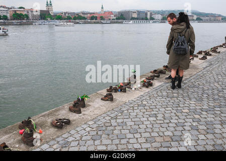 Tourists visit the Holocaust Memorial alongside the River Danube in the centre of Budapest, Hungary, bearing witness to the murder of Jews in WW II. Stock Photo