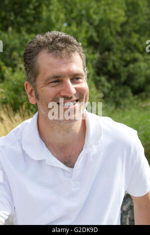 45-year old man with stubble smiling on a sunny summer vacation day in nature Stock Photo