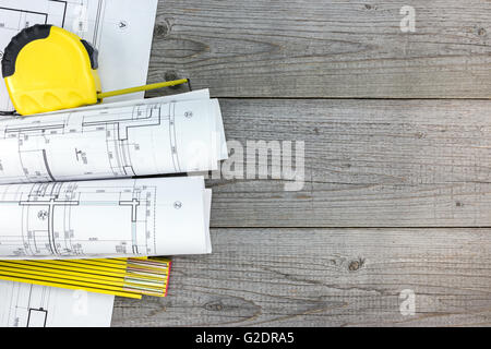 architectural blueprint rolls with tape measure and folding rule on wooden table Stock Photo