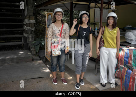 Women hard hat. Asian mother and two daughters wearing mandatory hard hats at the Sanctuary of truth Buddhist Hindu temple. Thailand, Southeast Asia Stock Photo