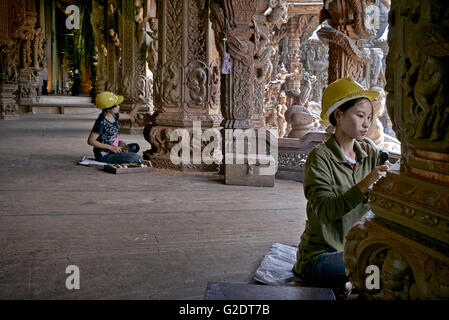 Craftswoman Thailand. Young female builders sculpting and carving wood at the Sanctuary of truth Buddhist Hindu temple. Pattaya Thailand S. E. Asia Stock Photo