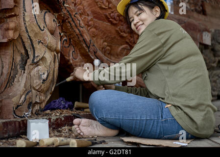 Young female builder sculpting and carving wood at the Sanctuary of truth Buddhist Hindu temple. Pattaya Thailand S. E. Asia Stock Photo