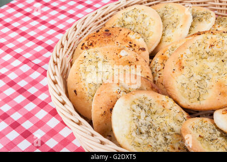 Round garlic flatbred in basket on red table Stock Photo