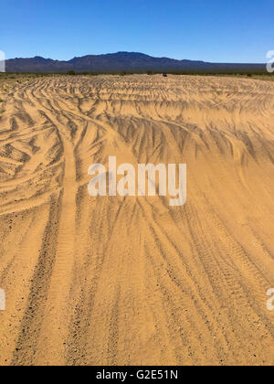 tire tracks in the desert in Nevada with a mountain range in the background and sky beyond Stock Photo