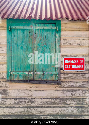 detail of old building in Gustavia St Bart's with a corrugated tin roof and shuttered window. Stock Photo