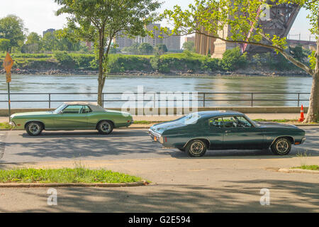 classic cars parked on a street in Queens, NY with a river nearby Stock Photo
