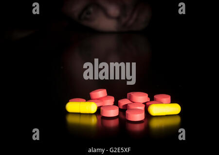 Narcotic addict with colored medicine on black table with reflection Stock Photo