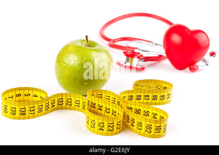 wet apple close-up with drops and yellow measure tape and red stethoscope and heart isolated on white Stock Photo