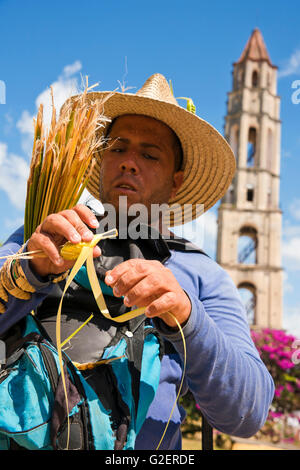 Vertical portrait of a man making a grasshopper from a sugar cane leaf in Valle De Los Ingenios, Cuba. Stock Photo
