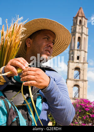 Vertical portrait of a man making a grasshopper from a sugar cane leaf in Valle De Los Ingenios, Cuba. Stock Photo