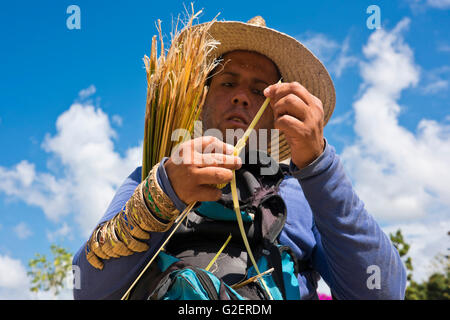 Horizontal portrait of a man making a grasshopper from a sugar cane leaf in Cuba. Stock Photo