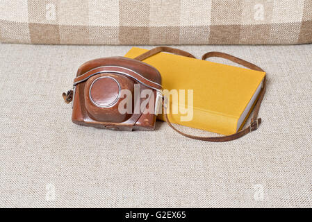 old vintage camera and yellow book on the sofa Stock Photo