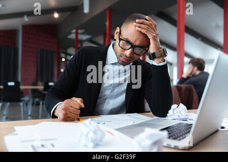 Focused businessman thinking over laptop Stock Photo