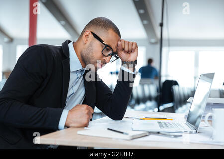 Serious smart businessman thinking about something using laptop in the office Stock Photo