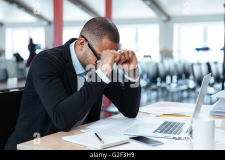 Overworked, depressed and exhausted businessman at his desk with a pile of work Stock Photo