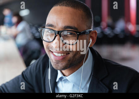 Close-up portrait of a smiling businessman wearing earphones at the office Stock Photo