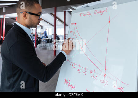 Handsome young businessman writing on a flipchart at the office Stock Photo
