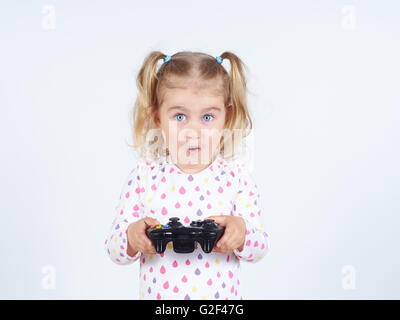 Little girl playing video games with gamepad in the hands. Stock Photo