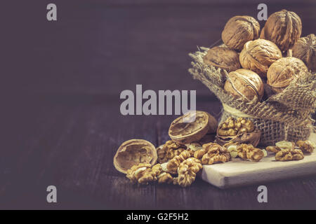 Walnuts in small burlap bag on dark wooden background. Copy space Stock Photo