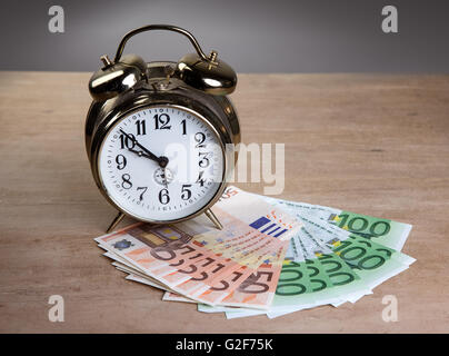 Time is Money concept shot with old mechanical Alarm Clock and Euro Banknotes Stock Photo