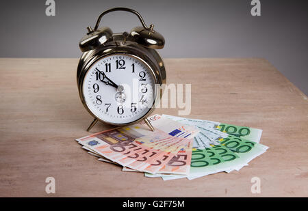 Time is Money concept shot with old mechanical Alarm Clock and Euro Banknotes Stock Photo