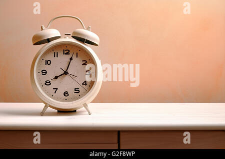 white vintage alarm clock on a wood table Stock Photo