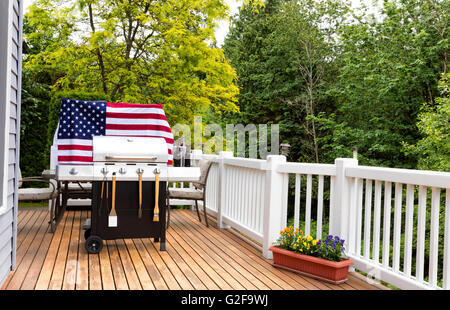 Home outdoor patio and barbecue cooker with bucket of cold bottled beer on ice with USA wooden flag in background. Stock Photo
