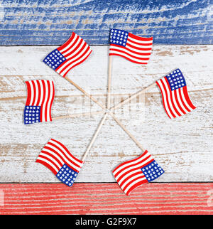 Small USA flags forming pinwheel formation on red, white and blue rustic boards. Fourth of July holiday concept for USA. Stock Photo