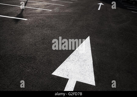 This way: bold white arrow on black asphalt. Many metaphorical uses. Space for copy. Stock Photo