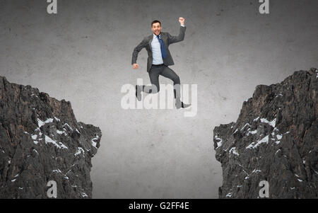 happy smiling businessman jumping between rocks Stock Photo