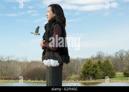 Profile of Woman Holding Basket of Eggs with Farm in Background Stock Photo