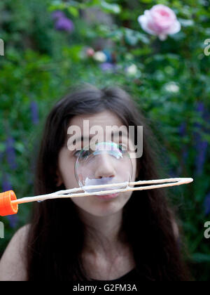 Young girl in back porch blowing bubbles Stock Photo
