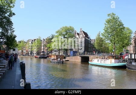 Old warehouses and houseboats moored along Prinsengracht canal (corner Nieuwe Leliegracht), Amsterdam, the Netherlands. Stock Photo