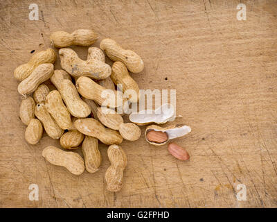 Monkey nuts aka peanuts aka groundnuts on board in shells. Stock Photo