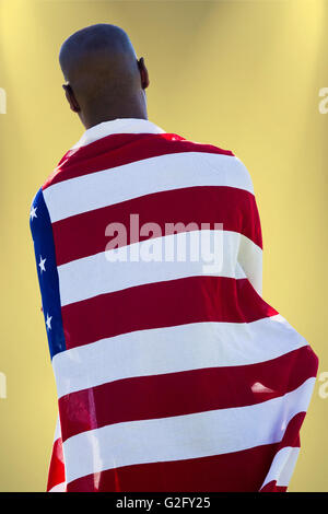 Composite image of rear view of man wearing american flag Stock Photo