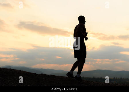 Silhouette of african american athlete jogging on sunset in mountains Stock Photo