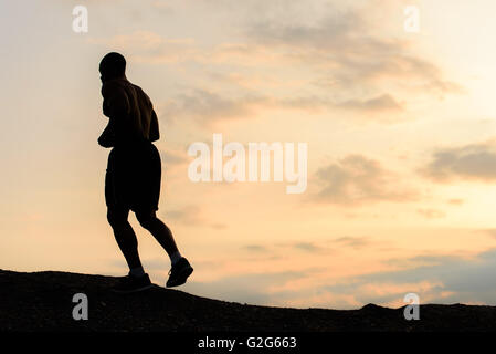 Silhouette of african american athlete jogging on sunset in mountains. Training outdoor. Sport and fitness concept Stock Photo