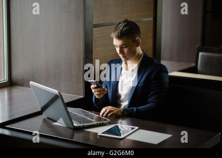 Portrait of a young businessman seeing on his smartphone in cafe. Stock Photo
