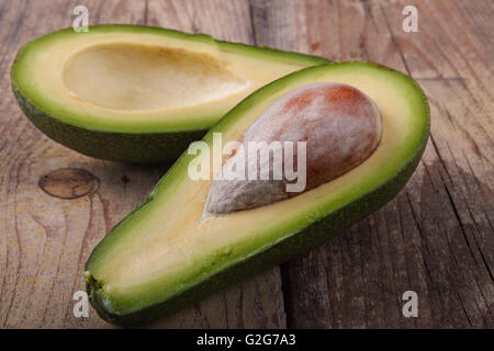Green Avocado  cut in half on old brown wood Stock Photo