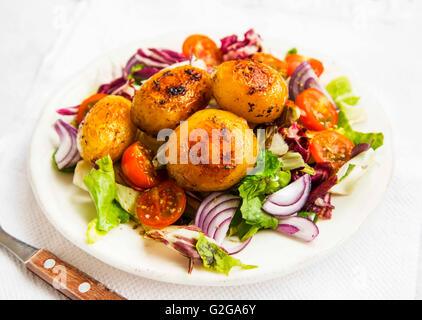 Roasted potatoes with vegetables salad on white plate Stock Photo