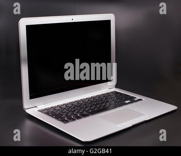 Slim silver color laptop on a dark background with black blank screen Stock Photo