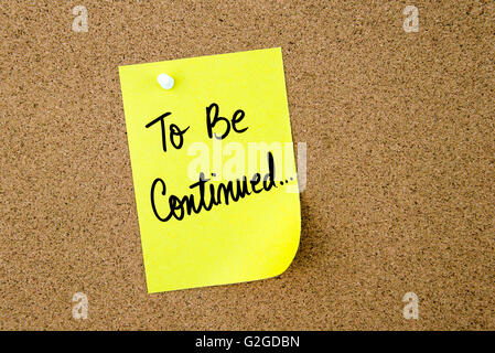 To Be Continued written on yellow paper note pinned on cork board with white thumbtack, copy space available Stock Photo