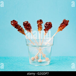 Five brown sugar stirrers in a glass on a light blue background. Stock Photo