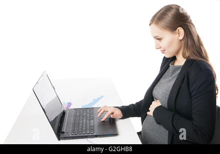 Side view of smiling pregnant woman at desktop working on laptop Stock Photo