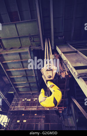 Vintage toned crane hook in old abandoned coal mine, focus on the hook. Stock Photo
